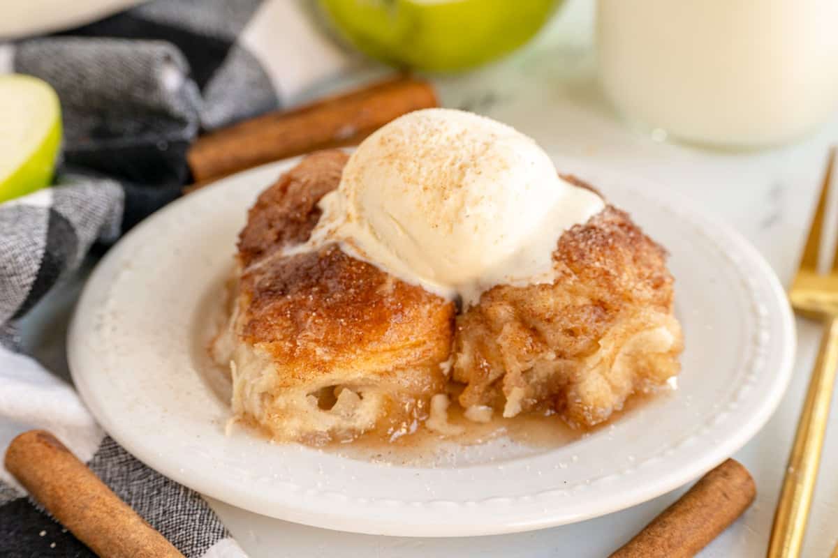 Three apple muffins lie on a white countertop. They all have pieces of oats on them. The forward is focused.