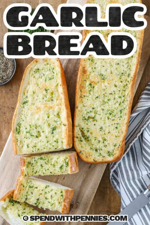 Homemade garlic bread on a serving board with writing 