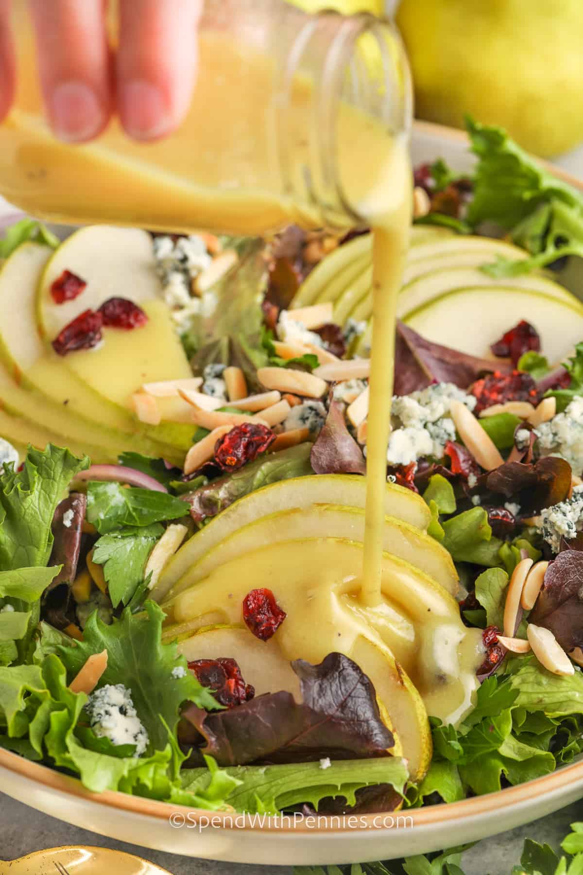 Dressing is poured on a pear salad