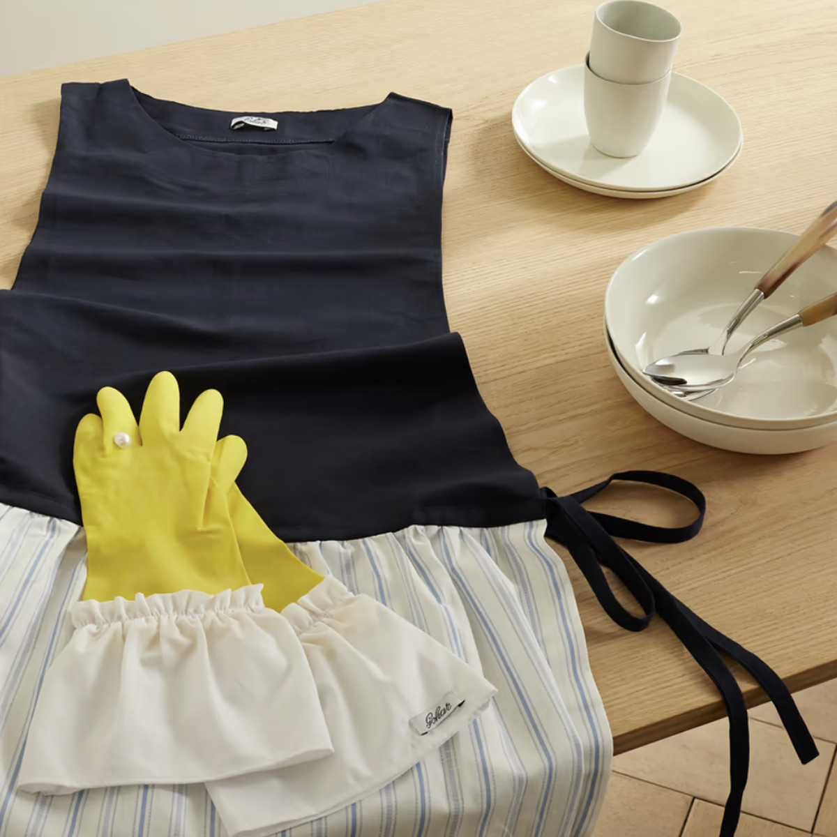 dark blue apron and yellow gloves on a counter next to a bowl with spoons.