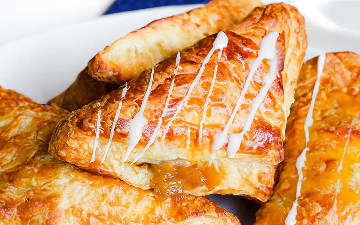 a platter full of apple turnovers drizzled with glaze.