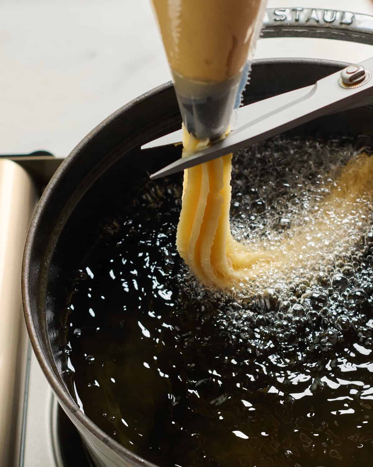 Churro dough transferring to hot oil. 